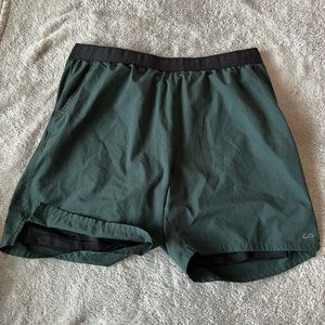 Men’s green and black athletic shorts with built in lining.
